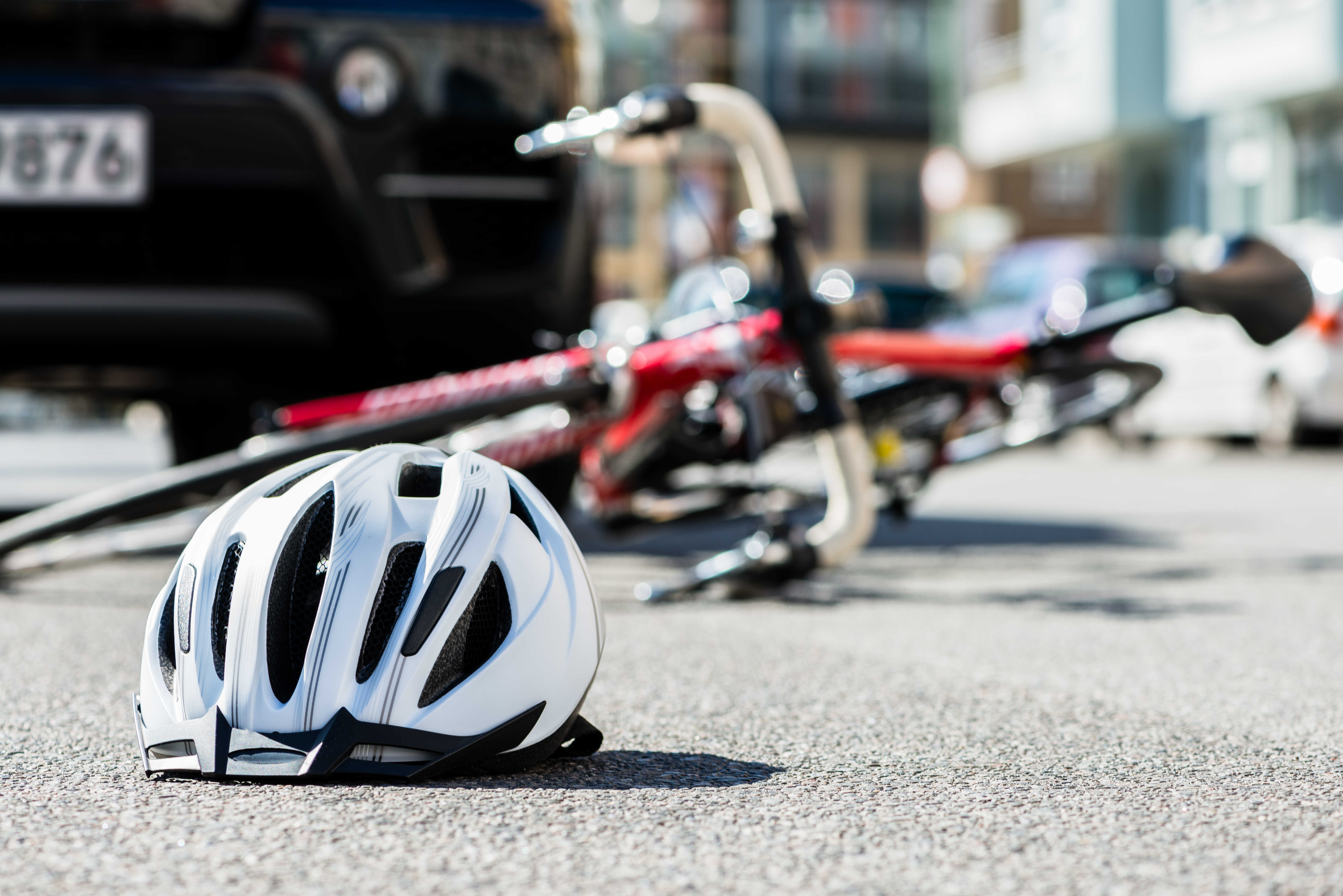 white bicycle helmet in front of overturned bicycle